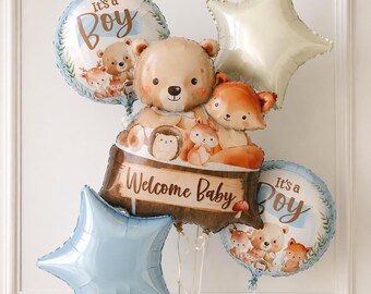 May include: A balloon bouquet featuring two round balloons with the text It's a Boy, two star-shaped balloons in cream and light blue, and a central shaped balloon depicting a bear, fox, hedgehog, and squirrel with the text Welcome Baby.