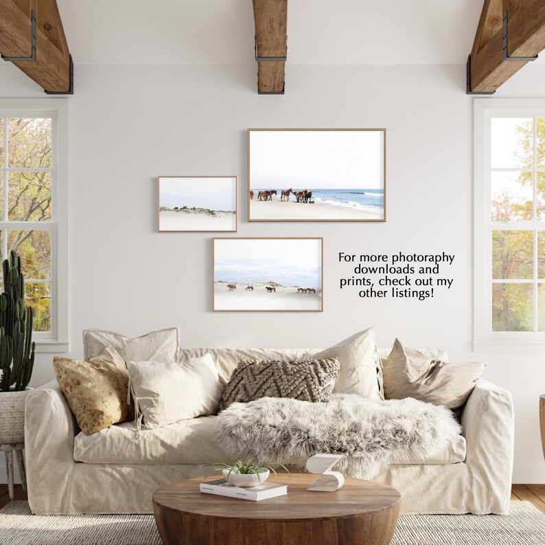 May include: Three framed landscape prints featuring horses on a beach and dunes. The prints are in light brown frames and hang on a white wall above a beige sofa. The text in the image says: For more photography downloads and prints, check out my other listings!