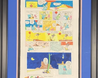 May include: A black and white comic strip featuring a character called "Krazy Kat" with the text "A pretty tall order, but I'll give it a try!" and "What's that I see?" in the first panel. The comic strip is framed in a black frame with a blue mat.