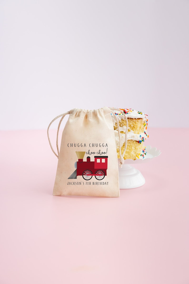 May include: A small, beige drawstring bag with a red train illustration and the text "CHUGGA CHUGGA choo choo! JACKSON'S 7TH BIRTHDAY".