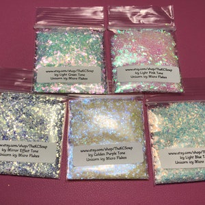 May include: Six small bags of iridescent glitter flakes, each with a label that reads "www.etsy.com/shop/TheKCSoap" and a color name: "Icy Light Green Tone", "Icy Light Pink Tone", "Icy Mirror Effect Tone", "Icy Golden Purple Tone", "Icy Light Blue Tone". Each bag is labeled "Unicorn icy Micro Flakes".