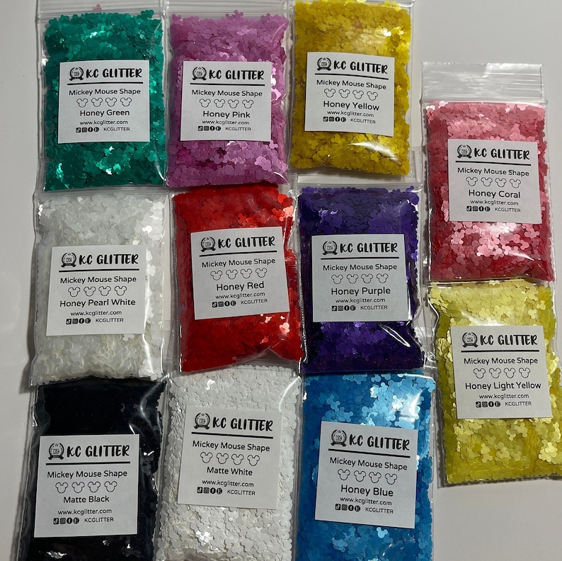 May include: Ten small bags of glitter shaped like Mickey Mouse heads. Each bag has a different color glitter and a label with the color name and the company name "KC Glitter".