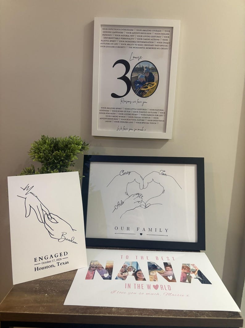 a display of various framed artworks and a sign, including a framed quote, a framed drawing of hands, and a sign that reads "To the best NANA in the world".