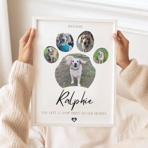 Op de afbeelding: Een ingelijste print met een pootafdrukontwerp, met vijf hondenportretten. De print bevat de naam "Ralphie" en de tekst "YOU LEFT A PAW PRINT ON OUR HEARTS."