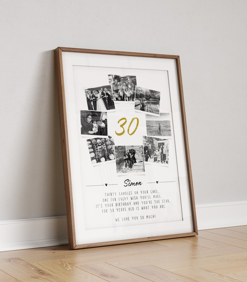 May include: A framed print with a wooden frame. The print features a collage of black and white photos surrounding the gold number "30". Below the photos is the name "Simon" and a message about a birthday. The print is leaning against a white wall.