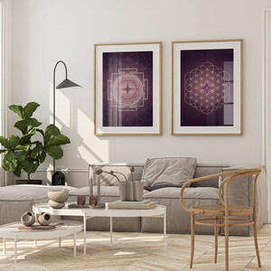 Pu&ograve; includere: Due stampe incorniciate di disegni geometrici in bianco su sfondo viola sono appese a una parete bianca sopra un divano grigio e una sedia di legno. I disegni sono un quadrato con una stella al centro e un cerchio con un motivo a fiore della vita.
