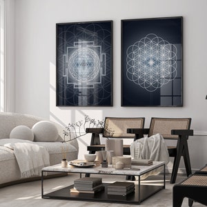 May include: Two framed wall art prints with geometric designs in a living room setting. One print features a complex white and blue geometric pattern on a dark blue background. The other print displays a flower of life pattern.