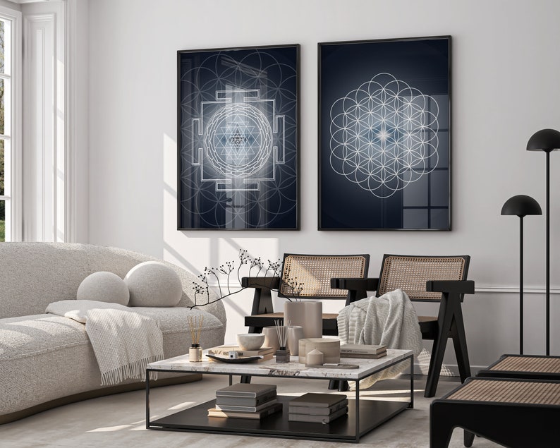 May include: Two framed wall art prints with geometric designs in a living room setting. One print features a complex white and blue geometric pattern on a dark blue background. The other print displays a flower of life pattern.