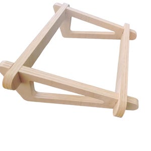 Peut inclure: Un présentoir en bois de couleur claire avec un design géométrique. Le présentoir est construit à partir de plusieurs morceaux de bois assemblés pour former un cadre robuste. Le présentoir est conçu pour contenir un objet.