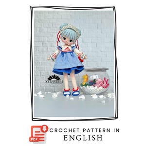 Peut inclure: Une poupée au crochet faite à la main, vêtue d'une robe bleue, d'un haut blanc et de chaussures bleues. La poupée a des cheveux bleu clair et un ornement de tête décoratif. Le texte "CROCHET PATTERN IN ENGLISH" est inclus.