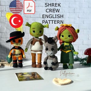 May include: Crochet amigurumi pattern for Shrek, Fiona, Donkey, and Puss in Boots. The pattern is available in English and includes instructions for making each character. The characters are made with green, brown, gray, and orange yarn.