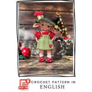Op de afbeelding: Een gehaakte pop in een groene jurk met rode accenten, een paddenstoelhoed en rode schoenen. De pop heeft een grillig ontwerp met een gedetailleerd haakpatroon. De tekst "CROCHET PATTERN IN ENGLISH" is inbegrepen.