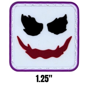 May include: Square patch featuring the Joker's face. The design includes black eyes, a red smile, and white face paint, framed by a purple border. The patch measures 1.25 inches.