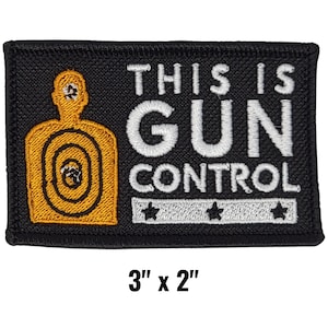 May include: Black rectangular patch with the words "THIS IS GUN CONTROL" in white block letters. A yellow target silhouette is on the left. The patch measures 3" x 2".