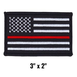 May include: Black and white embroidered patch featuring a stylized American flag design with a red stripe. The patch measures 3 inches by 2 inches.