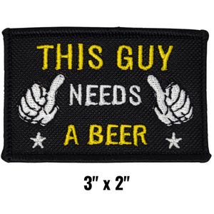 May include: Black rectangular patch with the text "THIS GUY NEEDS A BEER" in yellow and white. The patch features two white hand gestures and two white stars. The patch measures 3 inches by 2 inches.
