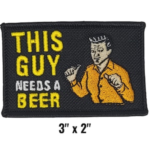 May include: Black rectangular patch with the text "THIS GUY NEEDS A BEER" in yellow and white. It features an illustration of a man in an orange shirt. The patch measures 3 inches by 2 inches.