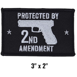 May include: Black rectangular patch with white text and a pistol graphic. The text reads "PROTECTED BY 2ND AMENDMENT". The patch measures 3" x 2". Two small star shapes flank the pistol graphic.
