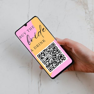 May include: A smartphone displaying a pink and yellow graphic with the text "BUY THE bride A DRINK" and a black and white QR code.