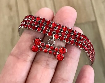 May include: Red rhinestone dog collar with a silver bone charm.