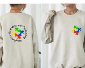 May include: A beige sweatshirt with a colorful puzzle piece design on the front and the words "Awareness, Understanding, Acceptance" in a circle on the back.