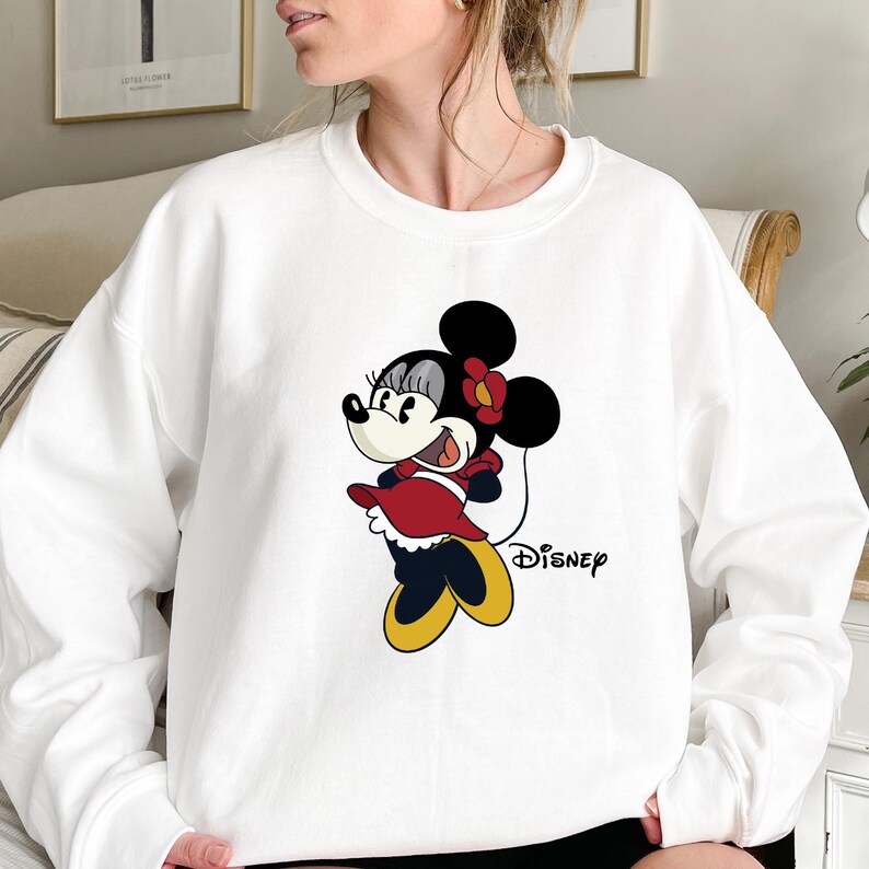 May include: White sweatshirt with a cartoon image of Minnie Mouse in a red dress and the word "Disney" printed on the front.
