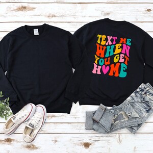 May include: Black sweatshirt with the text "Text Me When You Get Home" in colourful retro font with a pink heart.