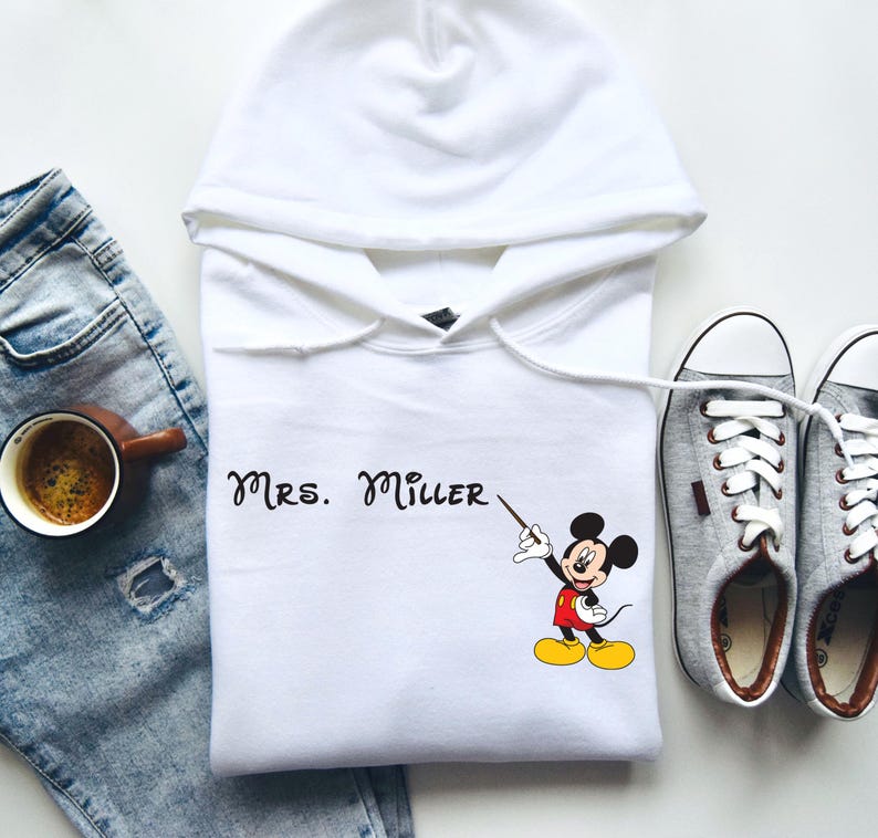 Peut inclure: Sweat-shirt &agrave; capuche blanc avec un motif de Mickey Mouse et le texte "Mrs. Miller" imprim&eacute; sur le devant.