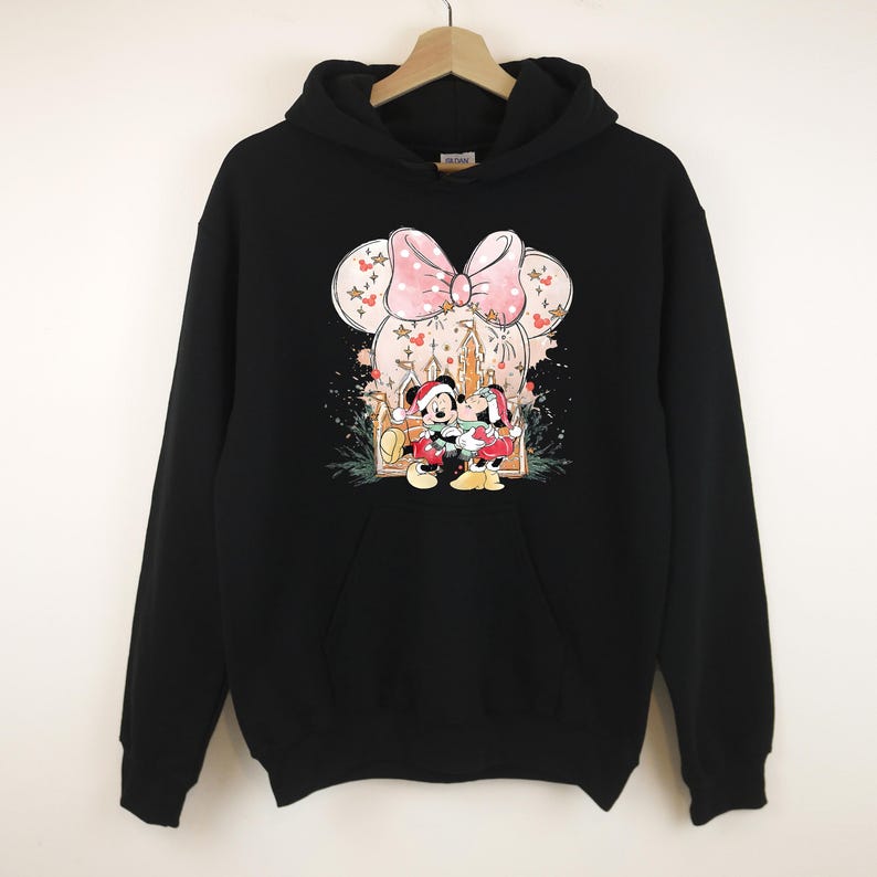 Peut inclure: Sweat-shirt &agrave; capuche noir avec un motif de Minnie et Mickey Mouse en tenue de f&ecirc;te. Le design comprend un n&oelig;ud rose, des motifs floraux et une sc&egrave;ne de vacances. Le sweat-shirt a une poche avant et une capuche &agrave; cordon.