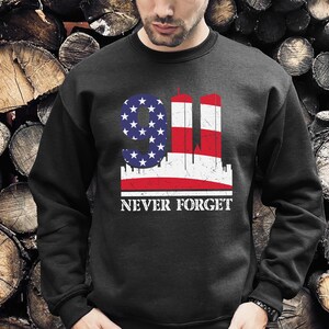 May include: Black sweatshirt with a graphic of the Twin Towers and the American flag with the text "9/11 Never Forget".