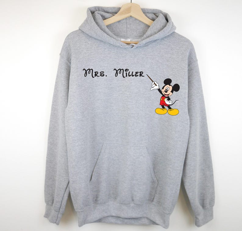 Peut inclure: Sweat-shirt &agrave; capuche gris avec le texte "Mrs. Miller" et une image de dessin anim&eacute; de Mickey Mouse tenant un pointeur.