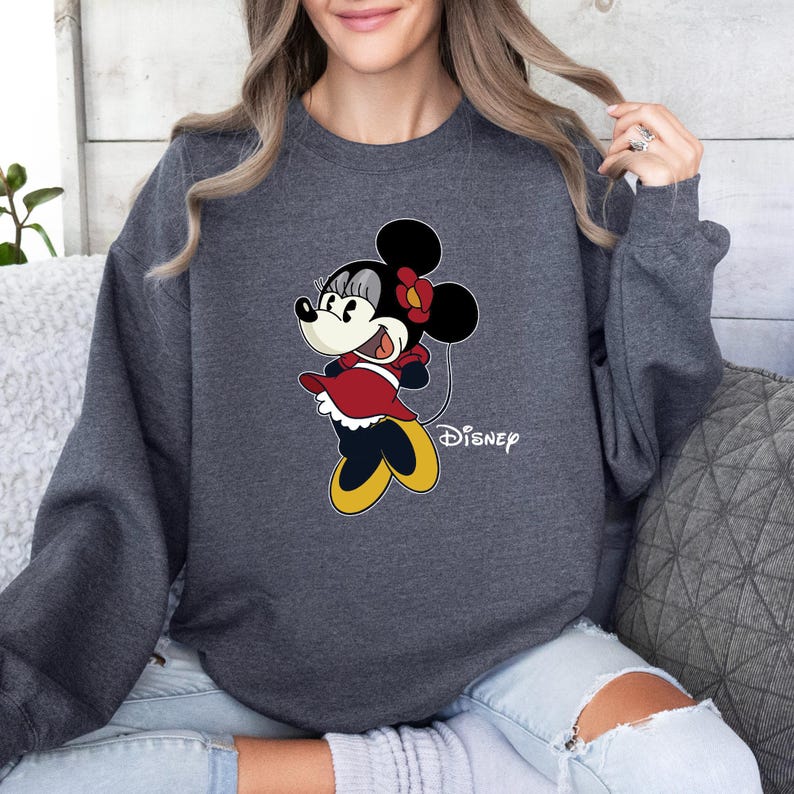 May include: A dark gray sweatshirt with a cartoon image of Minnie Mouse in a red dress and yellow shoes. The text "Disney" is printed below the image.