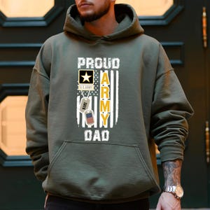 May include: A green hooded sweatshirt with the text "Proud Army Dad" and a US Army logo, a dog tag with the text "NAME" and a US flag.