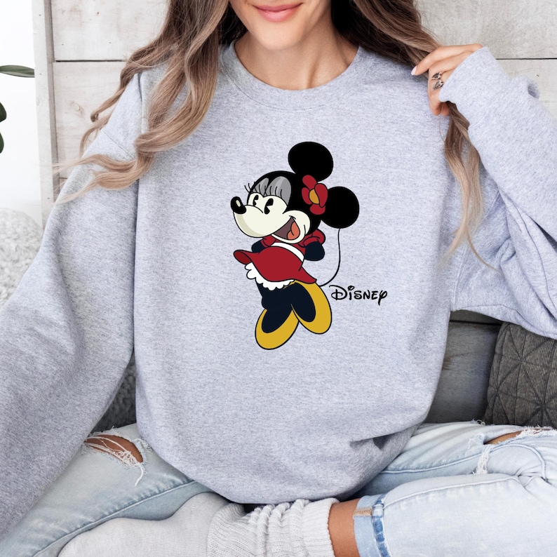 May include: A gray sweatshirt with a cartoon image of Minnie Mouse wearing a red dress and holding a balloon. The text "DISNEY" is printed below the image.