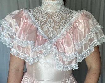 May include: A pink satin dress with a white lace collar and ruffles. The dress has a fitted bodice and a full skirt.