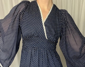 May include: A long-sleeved navy blue dress with white polka dots and white lace trim around the neckline and cuffs.