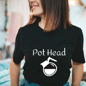 Puede incluir: Una camiseta negra con un gráfico blanco de una cafetera y el texto "Pot Head".