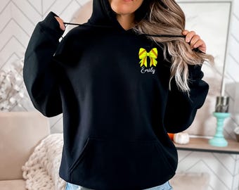 May include: Black hoodie with a yellow softball bow and the name "Emily" printed on the front.