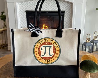 Peut inclure: Un sac fourre-tout en toile avec des poignées noires et un fond noir. Le sac présente un graphisme circulaire avec le texte "HAPPY PI DAY", le symbole pi et la date "3.14". Un nœud rayé noir et blanc est attaché à la poignée.