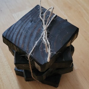 May include: A stack of four square black wooden coasters tied together with twine.