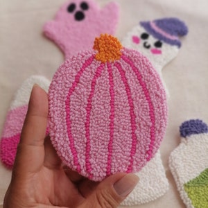 K&ouml;nnte beinhalten: Ein rosa-orangener Filz-K&uuml;rbis mit Stiel. Der K&uuml;rbis ist umgeben von anderen Filz-Halloween-Dekorationen, darunter ein Geist, ein Schneemann und eine Flasche.