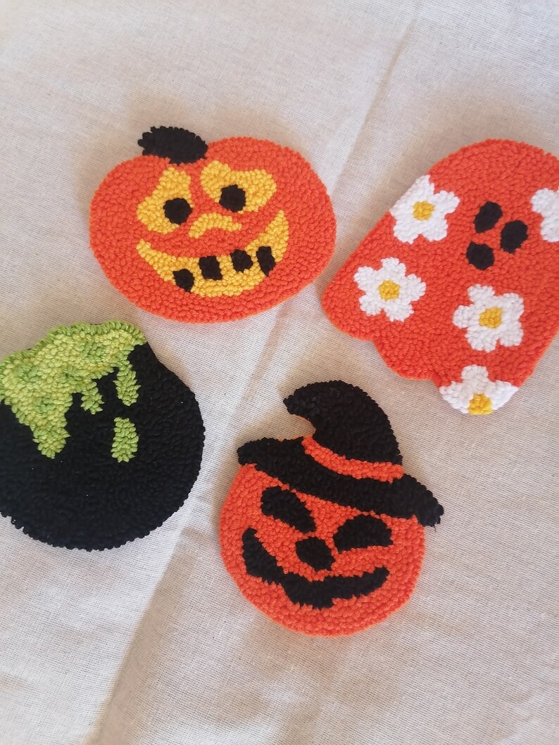 K&ouml;nnte beinhalten: Vier Halloween-Motive aus Filz. Eines ist ein K&uuml;rbis mit einem schwarzen Hut, ein anderes ist ein K&uuml;rbis mit einem schwarzen Gesicht, ein weiteres ist ein Geist mit wei&szlig;en Blumen und das letzte ist ein gr&uuml;ner und schwarzer Geist.