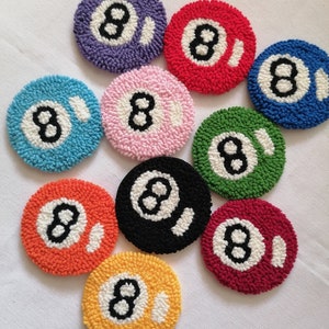 Könnte beinhalten: Zehn bunte runde Untersetzer mit einem weißen 8-Ball-Design. Die Untersetzer sind aus Garn gefertigt und perfekt, um Ihrem Zuhause einen Hauch von Spaß zu verleihen.