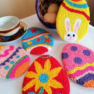 Può includere: Cinque ornamenti a punto ago in forma di uovo di Pasqua colorati. Gli ornamenti sono decorati con vari disegni, tra cui un coniglio, un fiore, pois e strisce. Gli ornamenti sono realizzati con filato e sono un modo divertente e festoso per decorare per Pasqua.