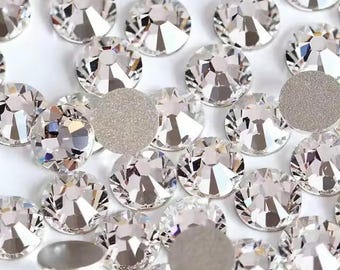 Puede incluir: Primer plano de numerosos pedrería claros y facetados con una superficie brillante y reflectante. Los brillantes redondos varían ligeramente de tamaño, creando un efecto brillante. Algunos tienen un respaldo plano plateado. Ideal para manualidades.