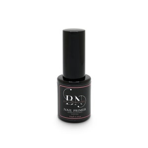 Puede incluir: Una botella negra de DND Billionaire Nail Primer. La botella tiene una tapa negra y una etiqueta con el nombre del producto y otros detalles. La etiqueta tiene un borde rosa y texto blanco. La botella contiene 13 ml de producto.