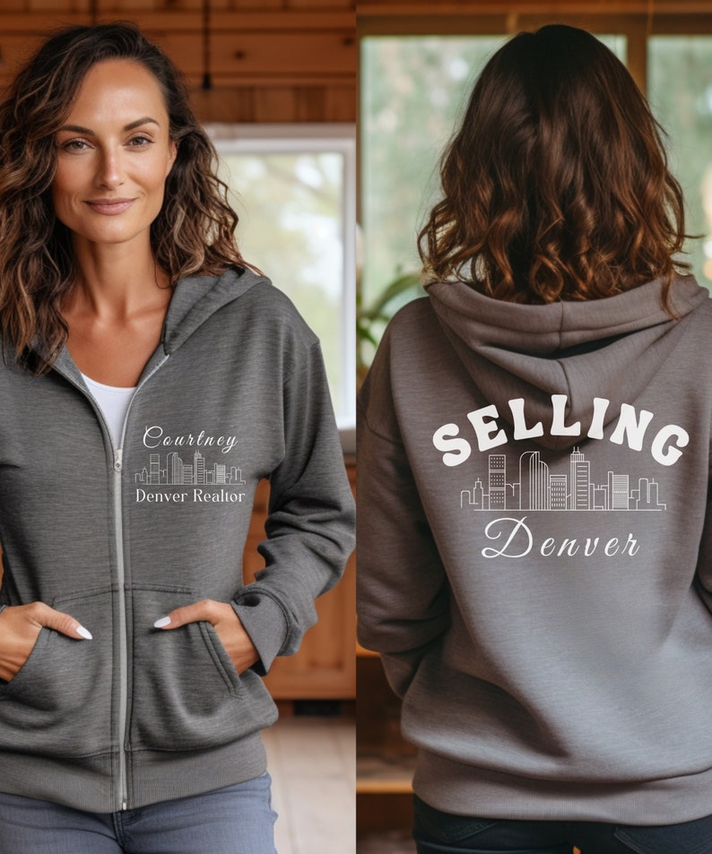 Puede incluir: Sudadera gris con cremallera y capucha con un gr&aacute;fico blanco de un horizonte de ciudad y el texto "Courtney Denver Realtor" en la parte delantera y "SELLING Denver" en la parte trasera.