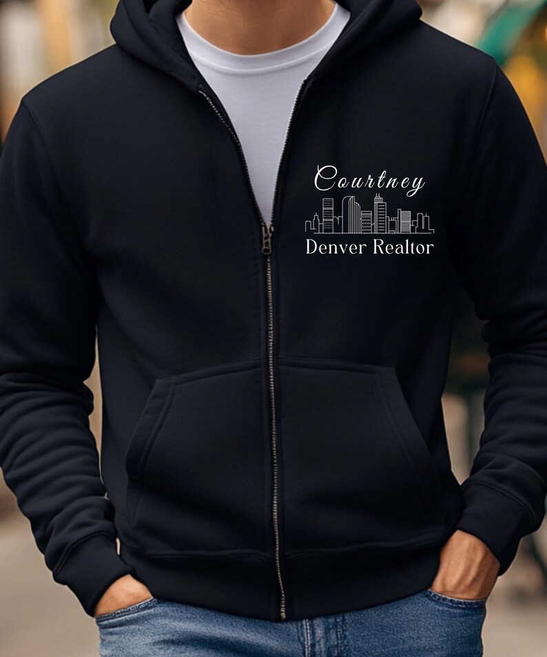 Puede incluir: Una sudadera con capucha negra con cremallera y un dise&ntilde;o blanco con un horizonte y el texto "Courtney Denver Realtor".