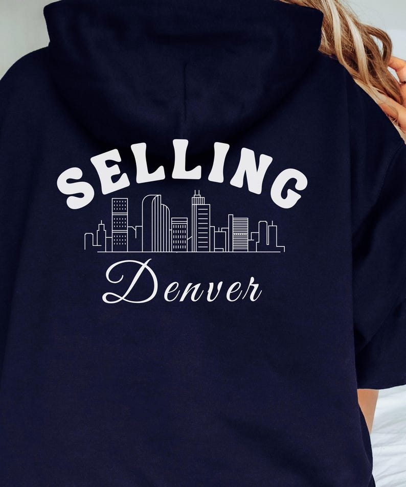 Puede incluir: Sudadera con capucha azul marino con un gr&aacute;fico blanco de un horizonte de ciudad y el texto "SELLING Denver".