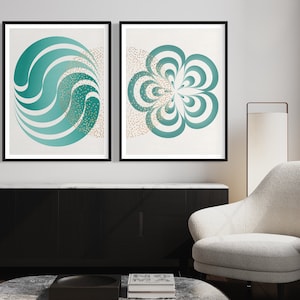 Puede incluir: Dos impresiones de arte abstracto enmarcadas con un esquema de color verde azulado y blanco. Las impresiones presentan formas geométricas con un patrón de remolino. Las impresiones están colgadas en una pared blanca sobre un gabinete negro.